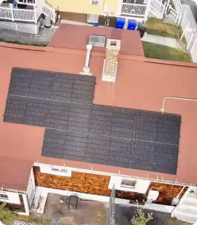 Aerial view of a residential roof featuring black solar panels, emphasizing renewable energy adoption and potential savings on electricity costs in Massachusetts.