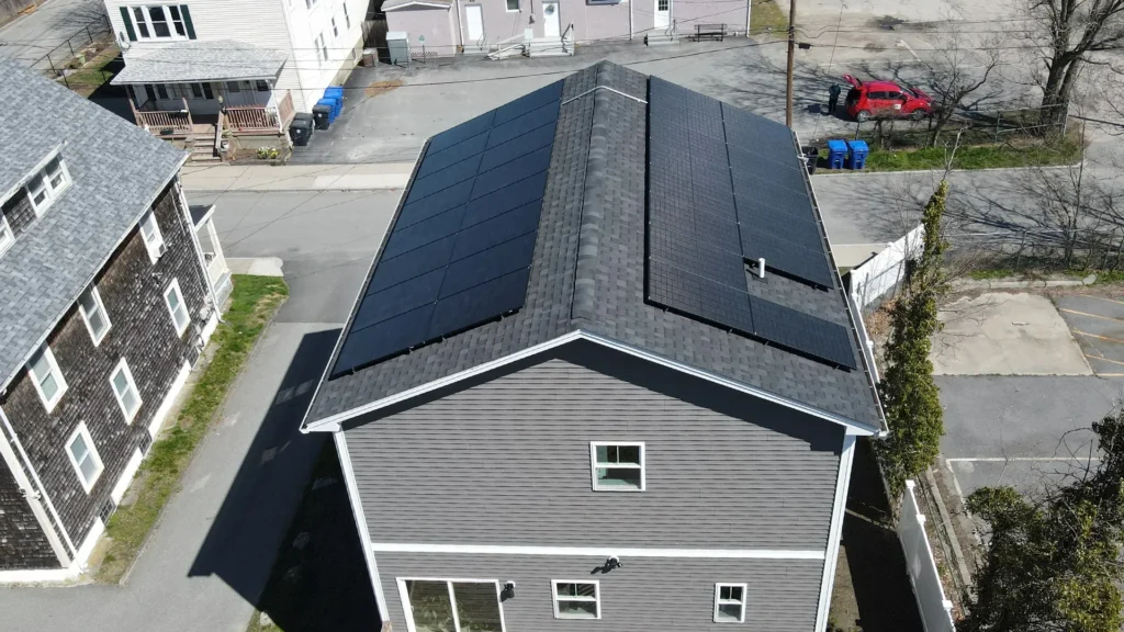 Aerial view of a house with solar panels installed on the roof, showcasing a modern energy solution for homeowners in New England considering solar energy options.